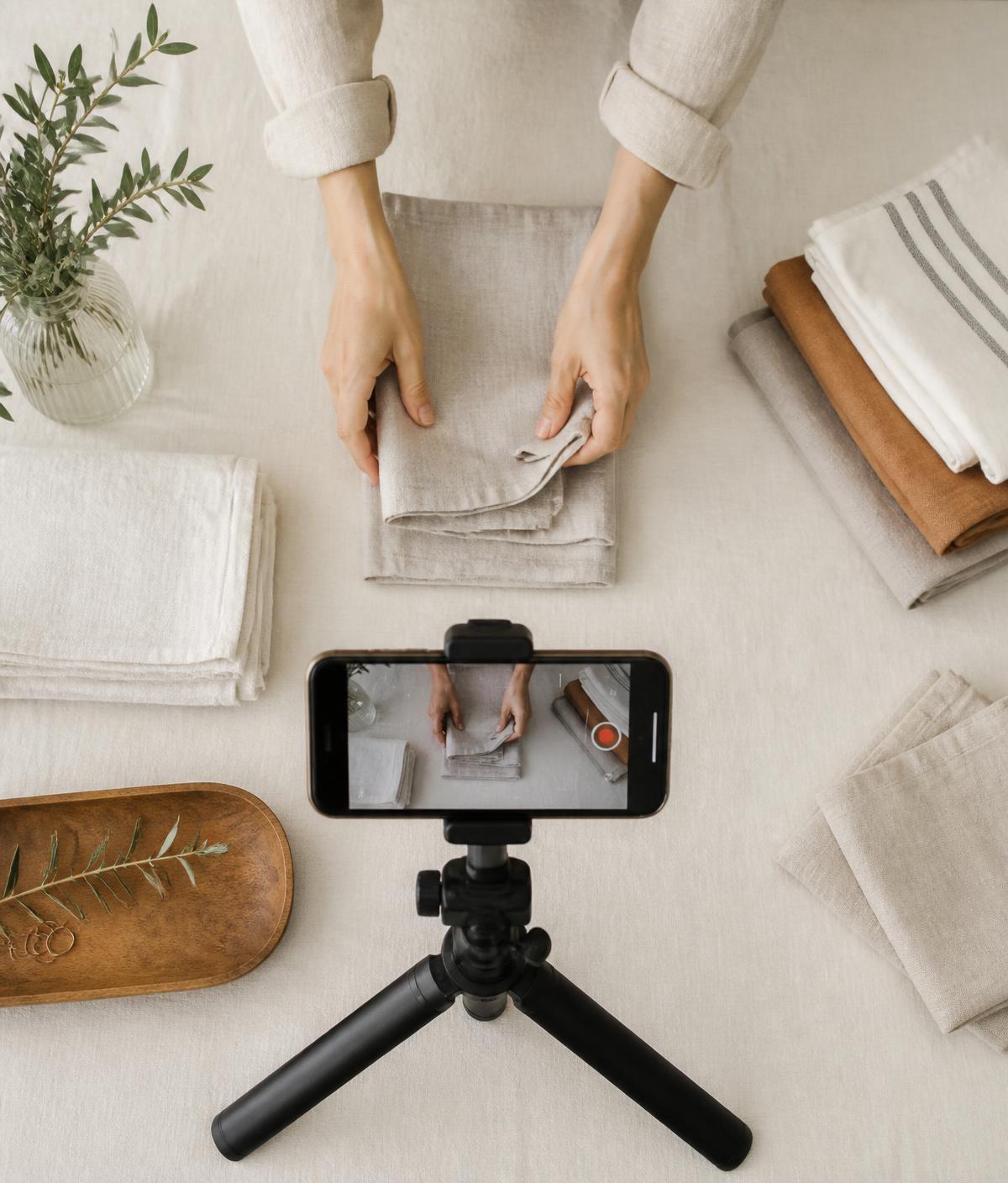 Móvil en un trípode grabando unas manos doblando ropa